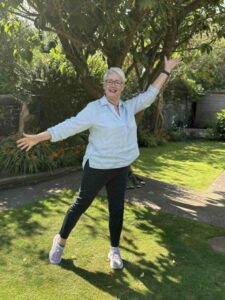 Fiona - posing confidently - arms wide open, big smile, in a garden